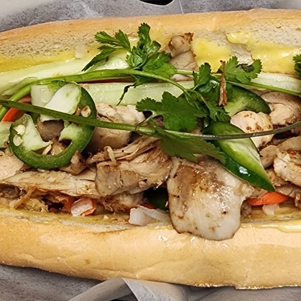 Close-up of a Vietnamese Banh Mi sandwich filled with grilled pork, cilantro, cucumber, and jalapeños.